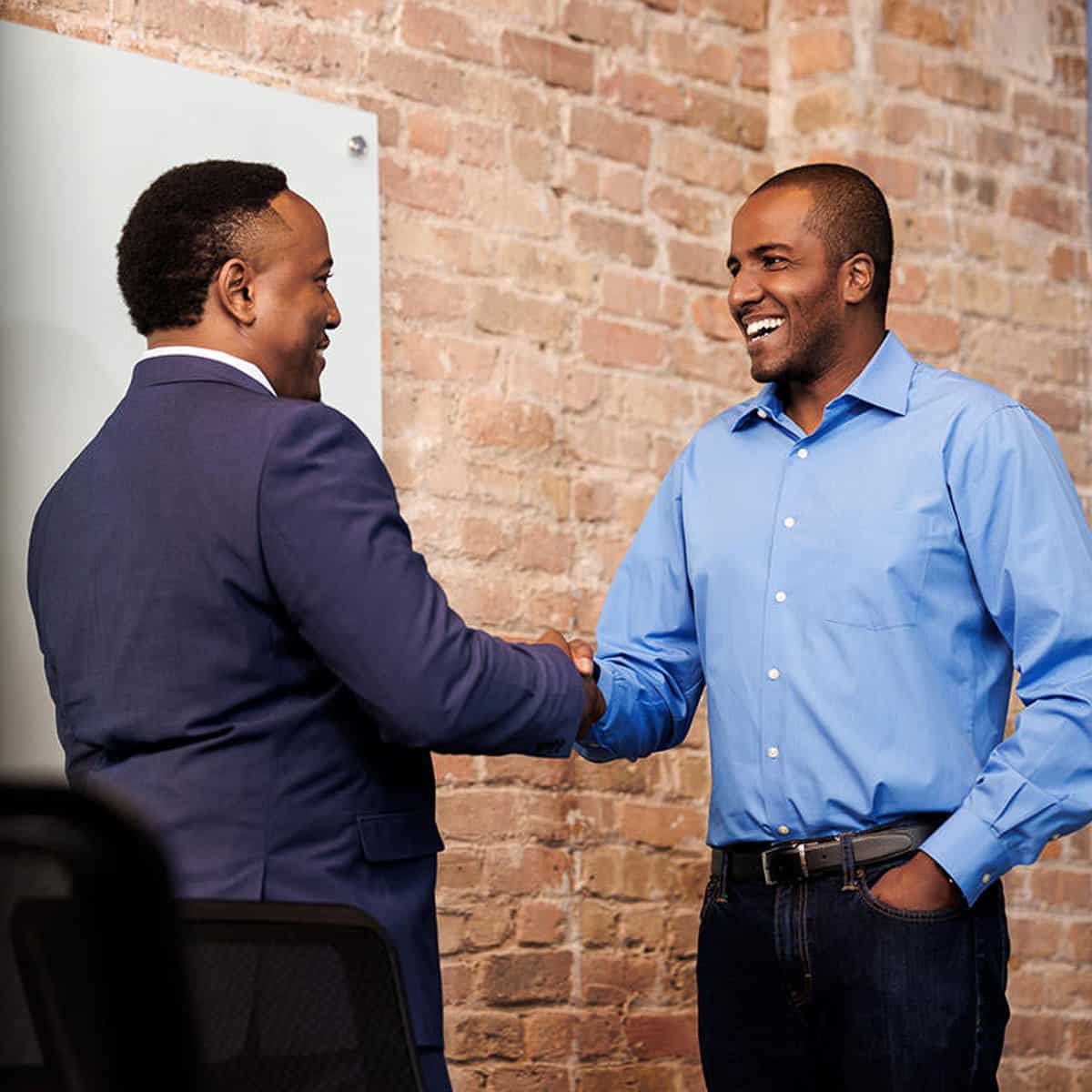 Chicago commercial photography featuring a corporate branding phot of two men shaking hands in front of a brick wall.