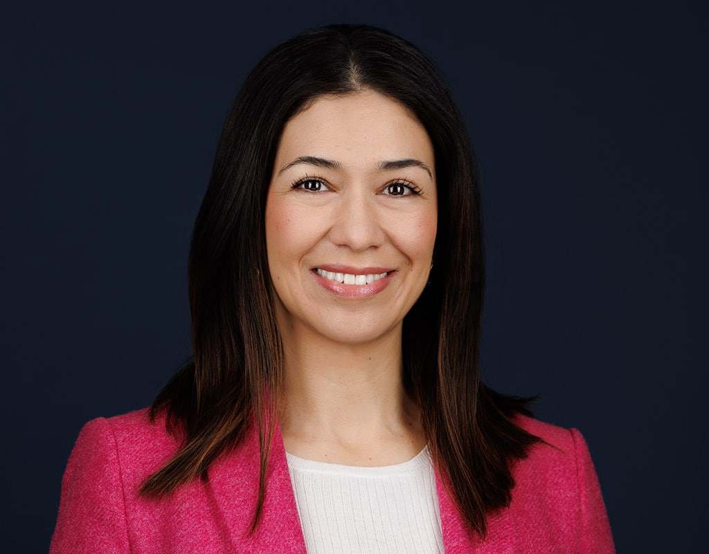 Confident woman in a pink blazer on a dark background, featured in Chicago corporate headshots.