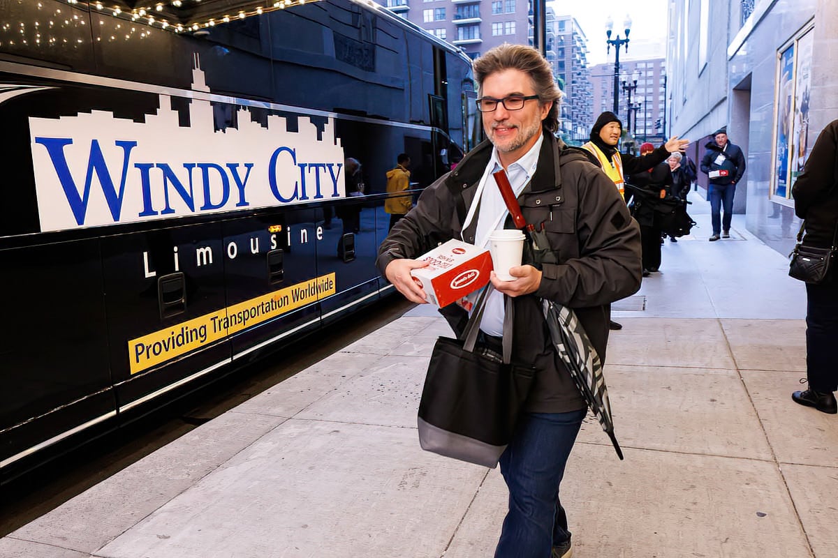 Event photography coverage of a man walking past a Windy City bus at a corporate conference.