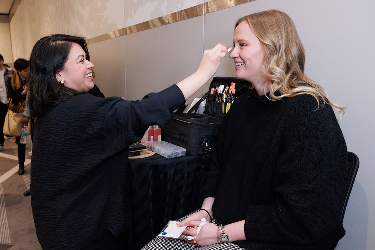 Makeup artist preparing an attendee for a Chicago Headshot Lounge session at a conference.