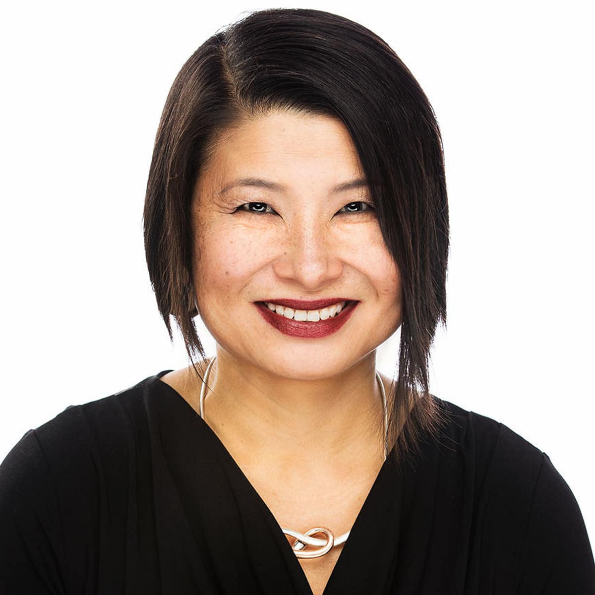 Chicago corporate headshot of a woman with short dark hair, smiling in front of a white background
