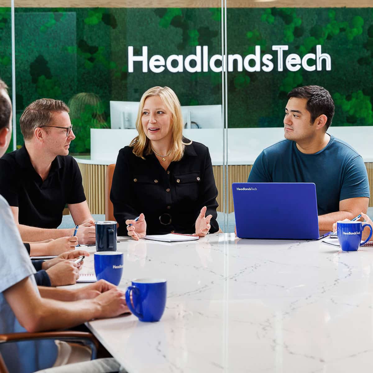 Chicago business photographer captures a leadership meeting at HeadlandsTech with four team members at a modern white conference table