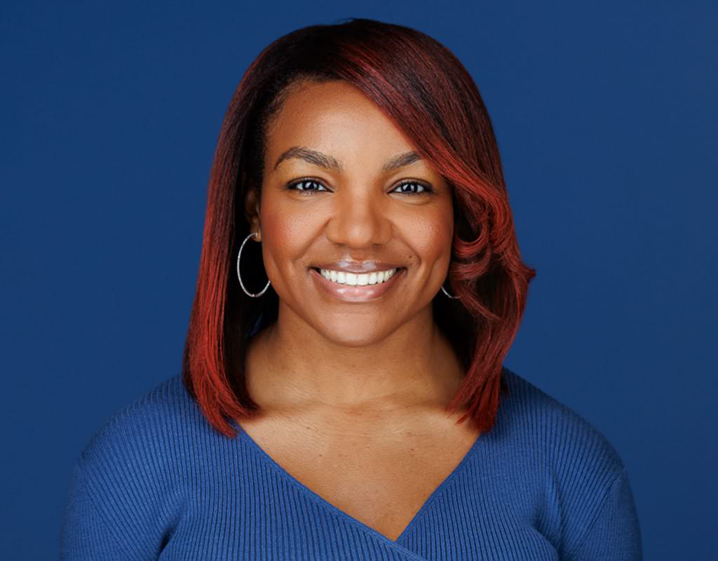 Headshot of a woman in a blue dress with hoop earrings, Chicago corporate headshots.