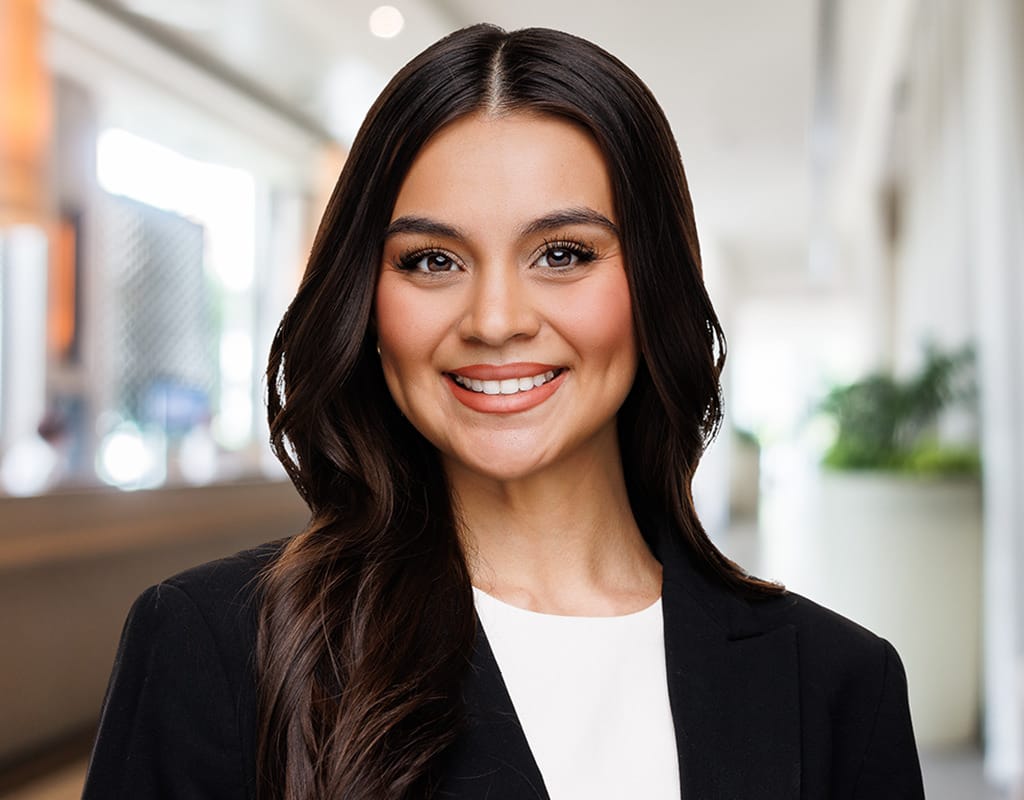 Professional headshot of a woman with long dark hair in a bright office hallway, by Chicago corporate headshot team at Tori Soper Photography.